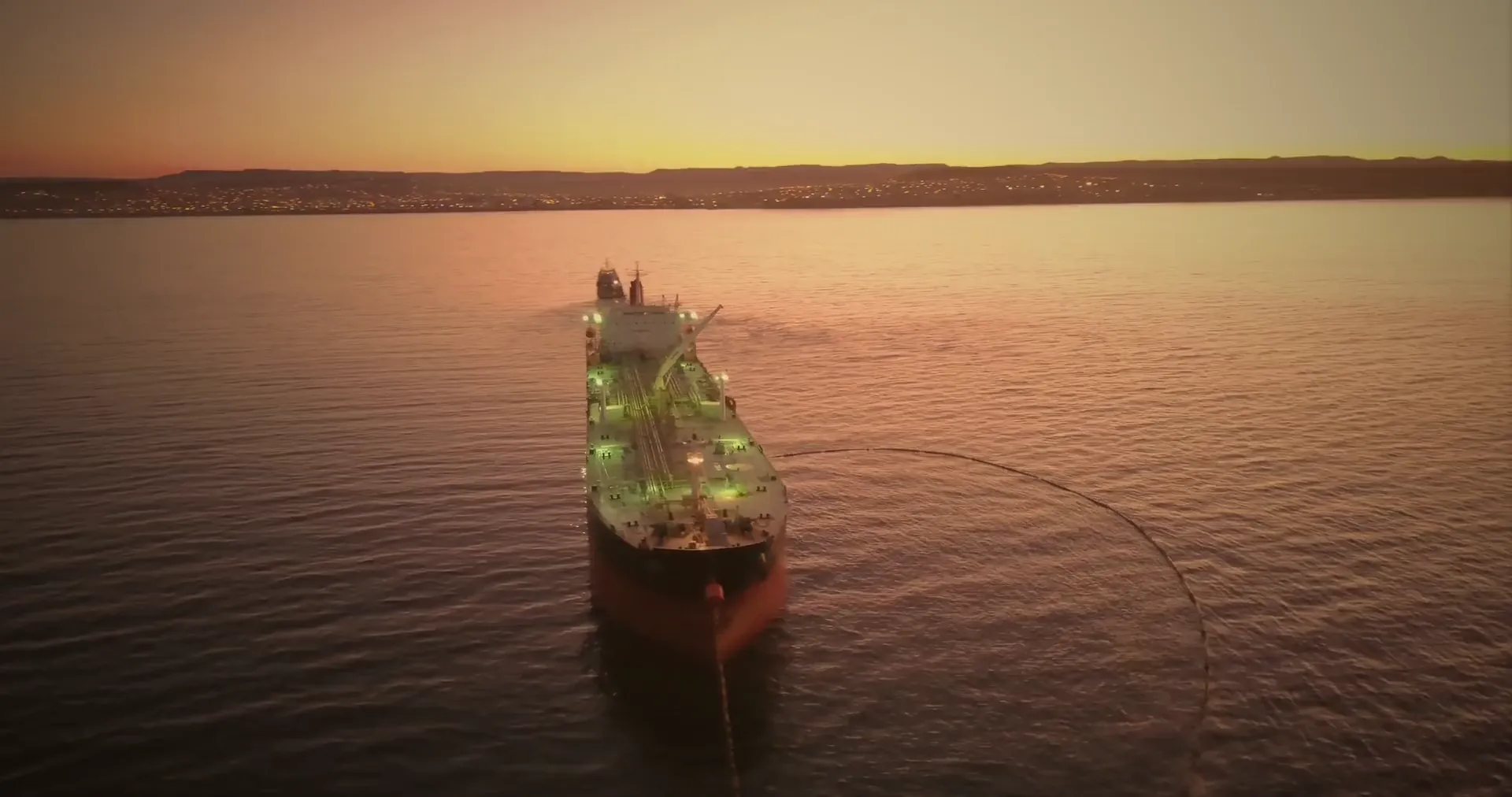 A tanker at anchor on calm water at sunset, seen from above